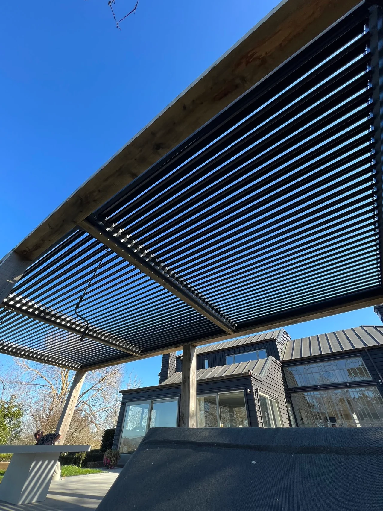 Large timber pergola with black louvres overhead