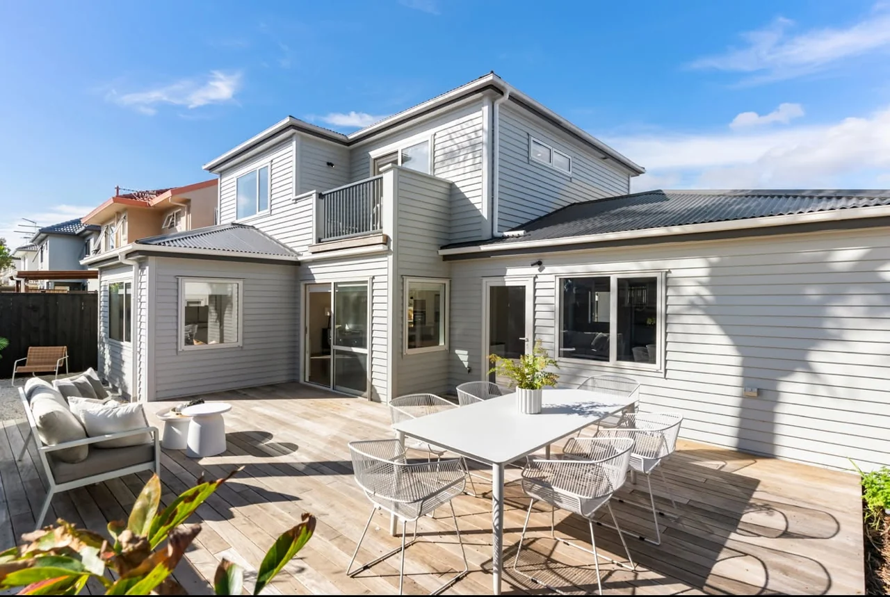 Finished timber deck with outdoor dining and lounge furniture beside a weatherboard home