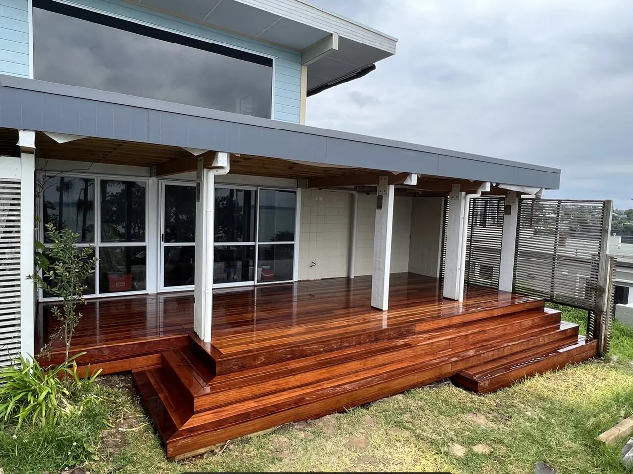 Finished timber deck and broad steps beneath a covered outdoor living area