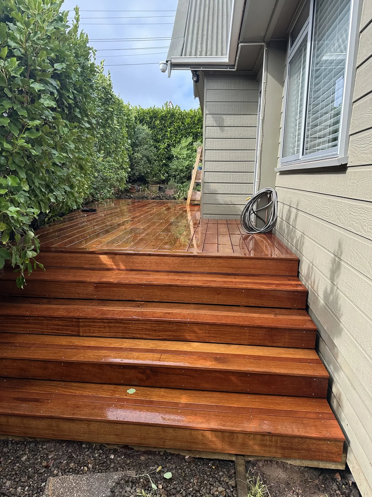 Reddish timber steps with inset lights beside a home